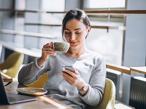 一位女子在咖啡廳愜意地喝著咖啡，在手機上查看個人化推播通知