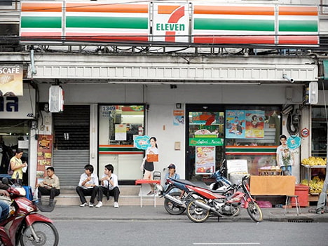 亞洲街邊景象，人們坐在 7-Eleven 店門口