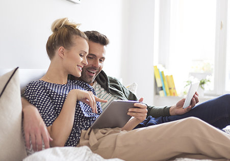 Frau und Mann sitzen auf dem Sofa und shoppen online über Tablet 